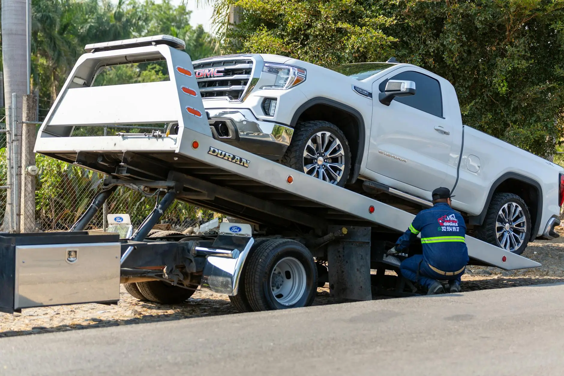 A Garrison Towing operator professionally securing a vehicle to a flatbed truck using damage-free straps.